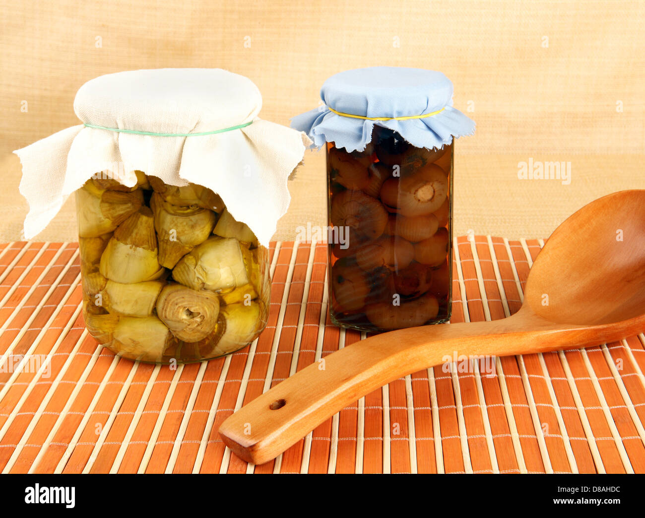 Les pots avec les artichauts et les oignons dans l'huile. Banque D'Images