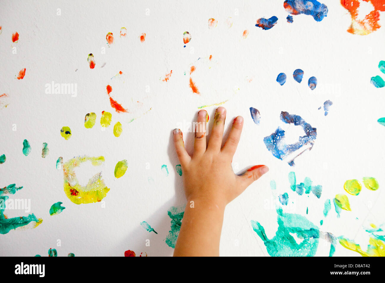 Main d'un bébé en peinture d'un mur blanc Banque D'Images