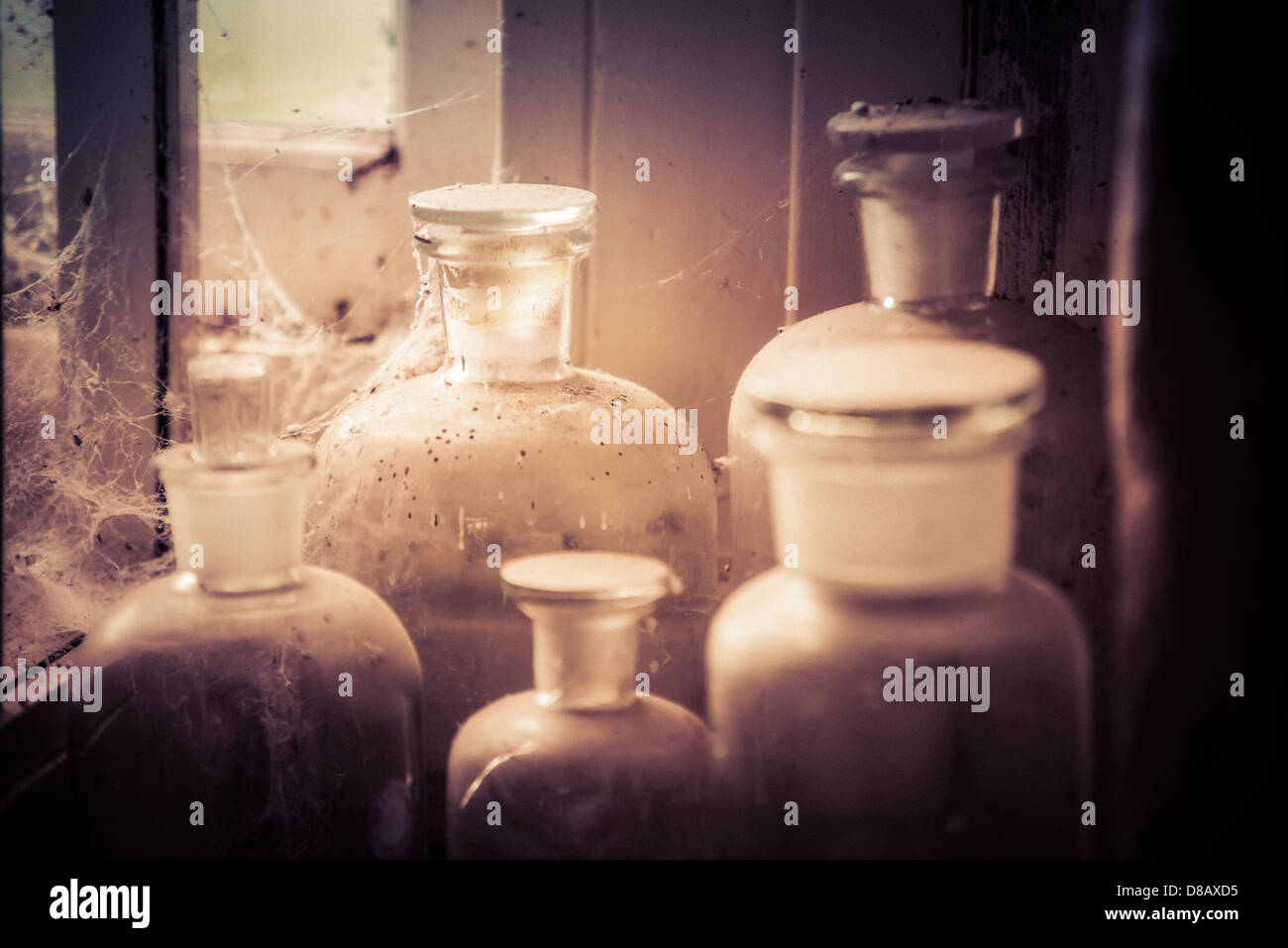 De vieilles bouteilles et contenants en verre recueillir la poussière et de bandes dans le coin d'une vieille salle de stockage. Version sépia. Banque D'Images