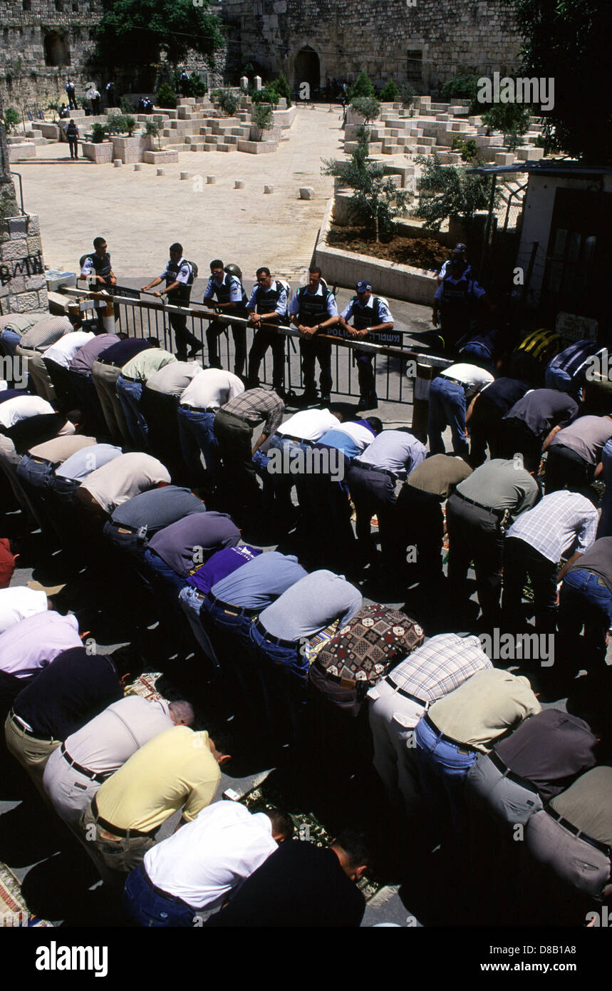 Des policiers israéliens montent la garde comme palestiniens hommes prier à l'extérieur de la mosquée Al Akza après interdit d'entrer sur le mont du Temple au cours de la prière du vendredi composé dans la vieille ville de Jérusalem-Est Israël Banque D'Images