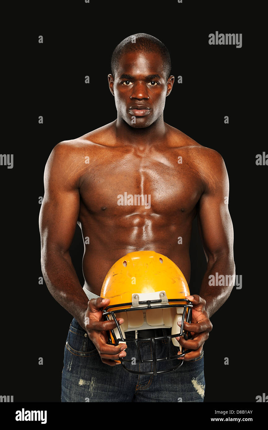 Young African American Man holding a Football Helmet isolé sur un fond sombre Banque D'Images