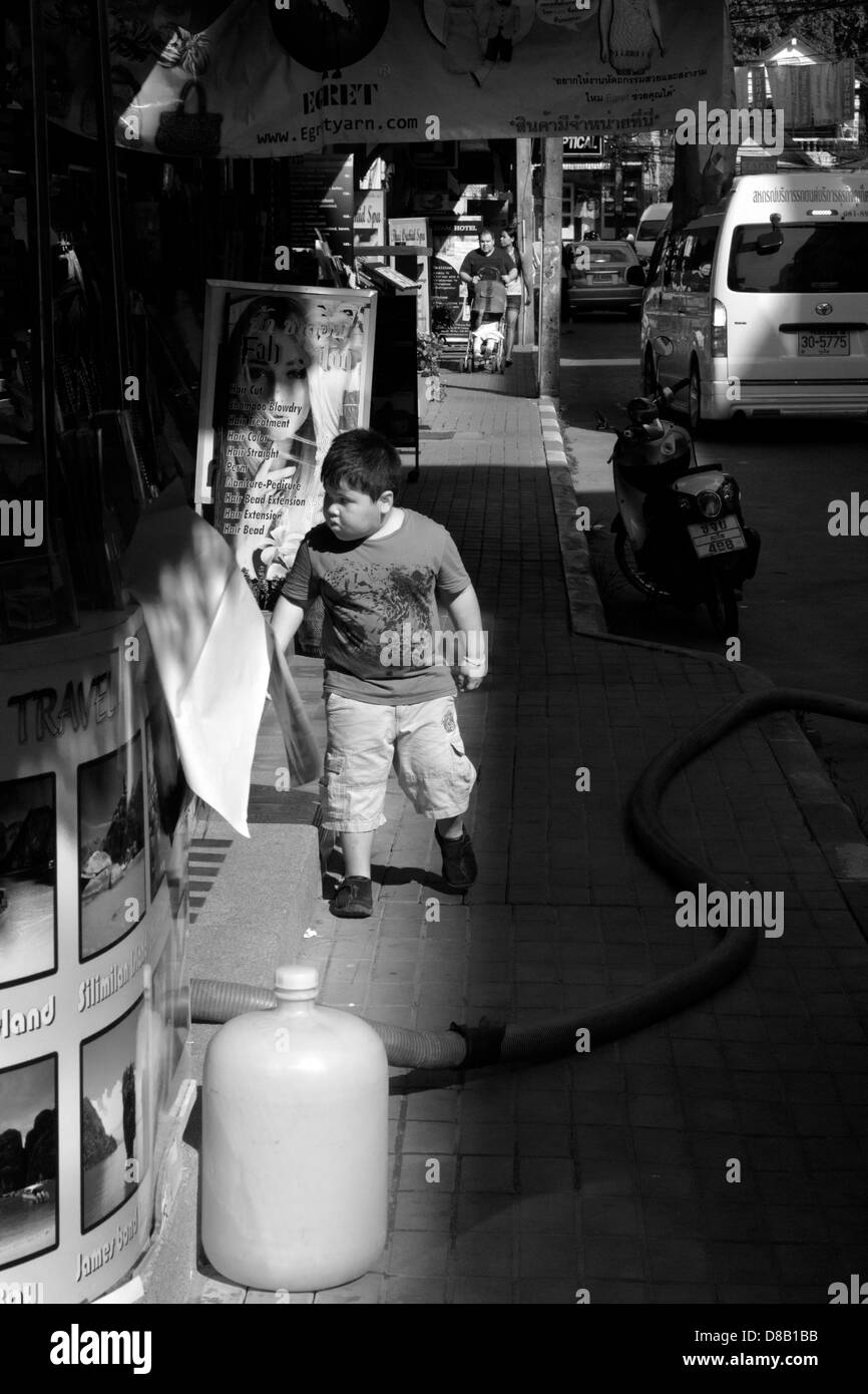 PATONG, Phuket, Thailand 28 FÉVRIER 2012 : garçon regarde à l'intérieur salon de coiffure sur Banzann Road Banque D'Images