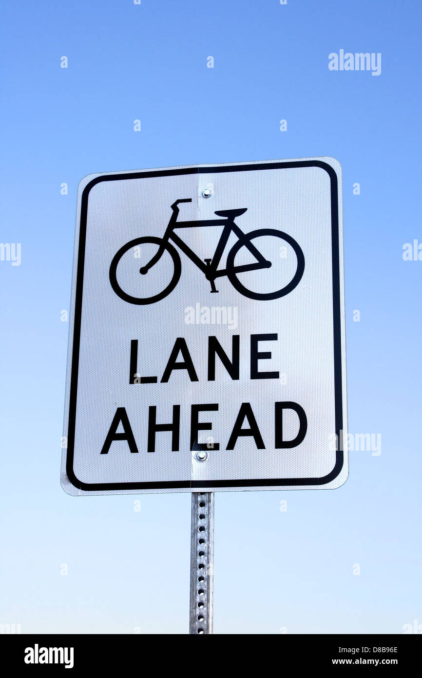 Cette photo montre un panneau de signalisation indiquant une piste cyclable devant vous. L'image met en évidence le symbole et le message clairs destinés aux conducteurs et aux cyclistes, mettant l'accent sur la sécurité routière et la sensibilisation des motards. Banque D'Images