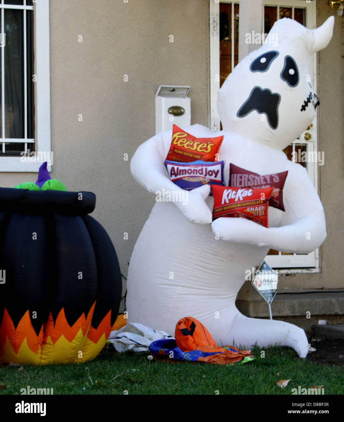 Une décoration de pelouse pour Halloween avec une figure fantôme entourée de bonbons. La scène évoque l’esprit festif d’Halloween, avec une ambiance effrayante mais ludique. Banque D'Images