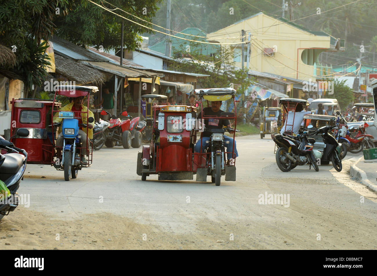 Tricycles et les motos sur la route dans la ville côtière de Puerto Galera. L'île de Mindoro, Philippines Banque D'Images