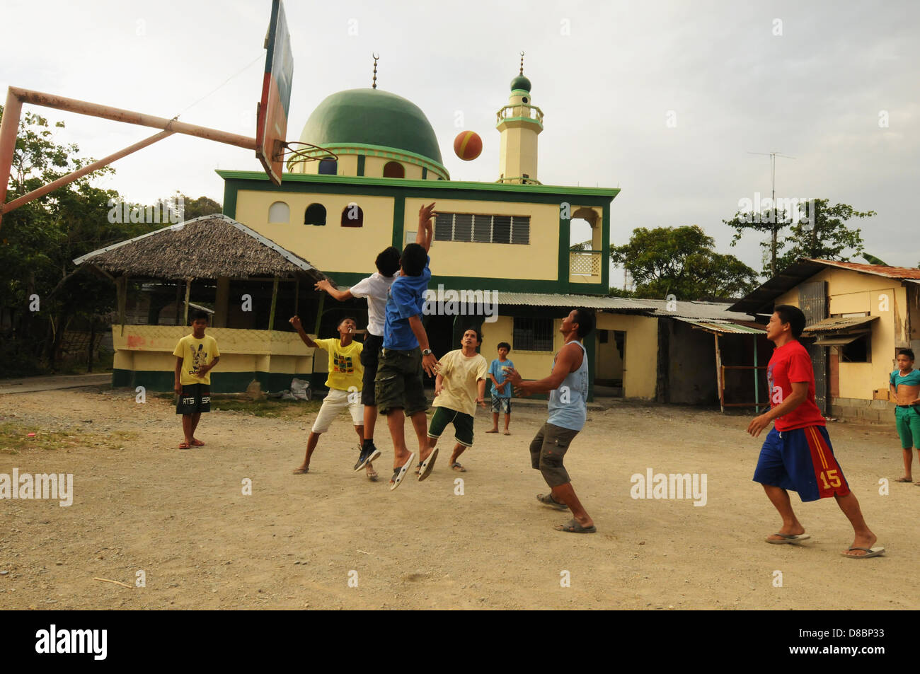 Des hommes jouer au basket-ball à l'arrière-cour près d'une mosquée dans la ville côtière de Puerto Galera. L'île de Mindoro, Philippines Banque D'Images