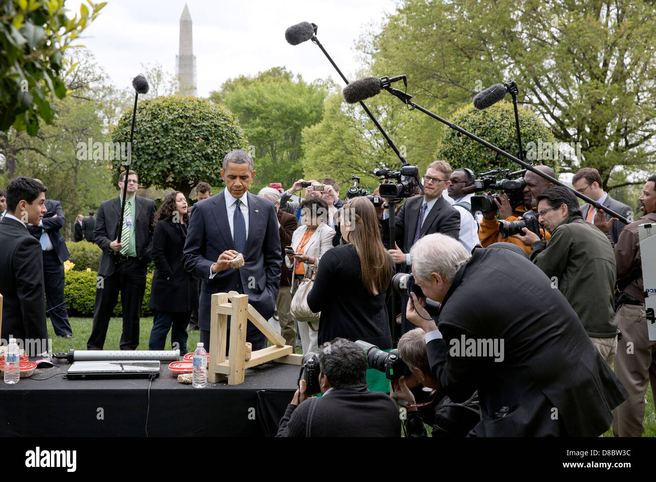 Le président américain Barack Obama ressemble à un morceau d'un carburant de substitution au bois fabriqué à partir de déchets de biomasse tandis que les projets présentés à la Maison Blanche Expo-sciences dans le jardin de l'Est de la Maison Blanche le 22 avril 2013 à Washington, DC. Jon, Kubricki Zarych, gauche et Bridget, centre, de Pinelands Eco Regional High School à Little Egg Harbor, New Jersey), ont présenté leurs mini-presse qui transforme les déchets de biomasse bois-alternative viable en combustible pour la cuisine. Banque D'Images