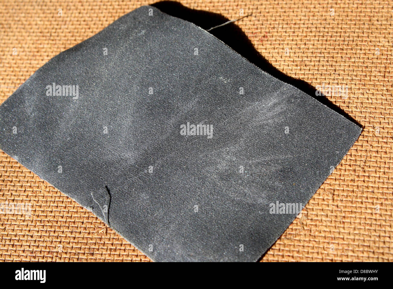 L'image montre un morceau de papier abrasif ultra-fin gris utilisé, couramment utilisé pour lisser les surfaces ou les préparer pour la peinture. La texture fine du papier de verre fournit une qualité abrasive douce, permettant un ponçage délicat de matériaux comme le bois, le métal ou le plastique. Ce type de papier de verre est généralement utilisé pour des finitions ou des travaux détaillés dans divers projets d'artisanat et de réparation. Banque D'Images
