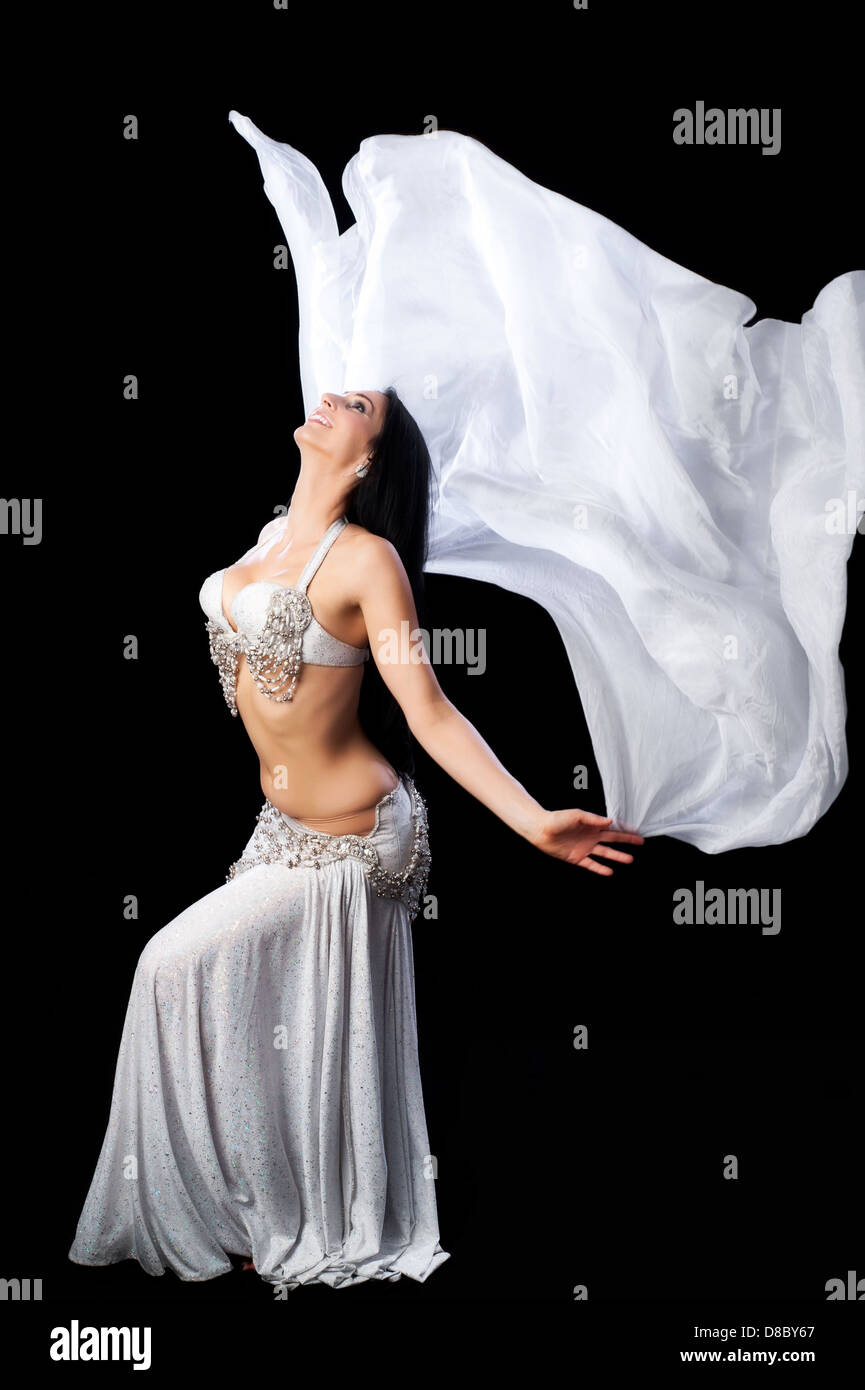 Une belle brunette, bellydancer danse avec un fluide en soie de couleur argent, voile. Isolé sur un fond noir. Banque D'Images