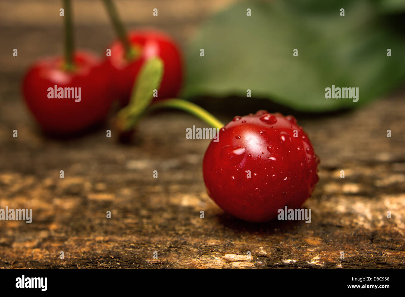 Cerise rouge savoureux avec des gouttes d'eau sur la table en bois. Banque D'Images