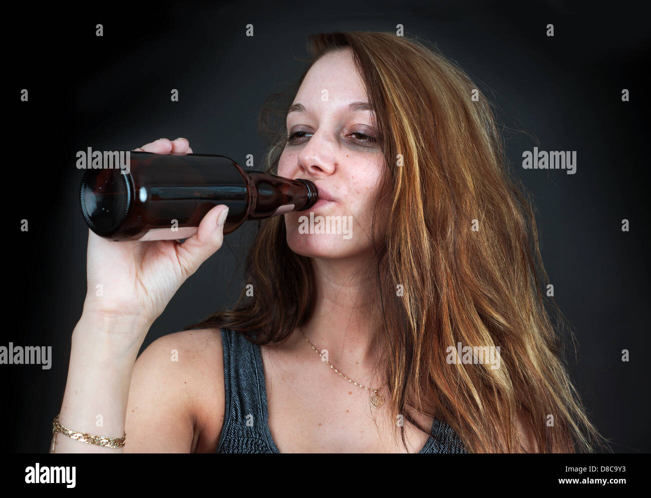 Portrait de jeune femme ivre de boire une bière sur fond noir Banque D'Images