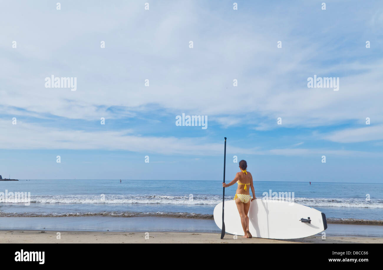 Woman on beach with paddle board Banque D'Images