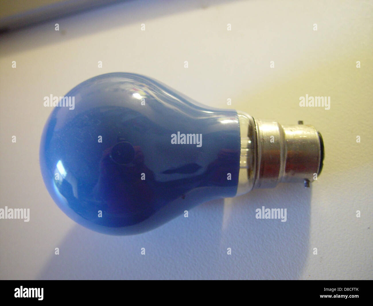 Un globe lumineux bleu avec un raccord à baïonnette, couramment utilisé dans les appareils d'éclairage ménagers. Le raccord à baïonnette permet une installation facile et une fixation sécurisée de l'ampoule. Banque D'Images