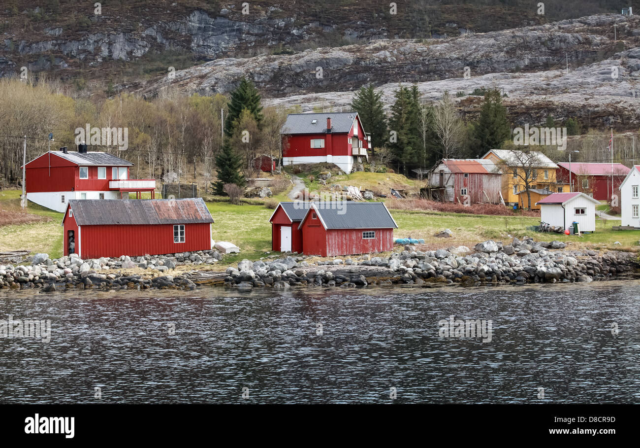 Petit village traditionnel norvégien avec des maisons en bois rouge sur la côte rocheuse au printemps Banque D'Images