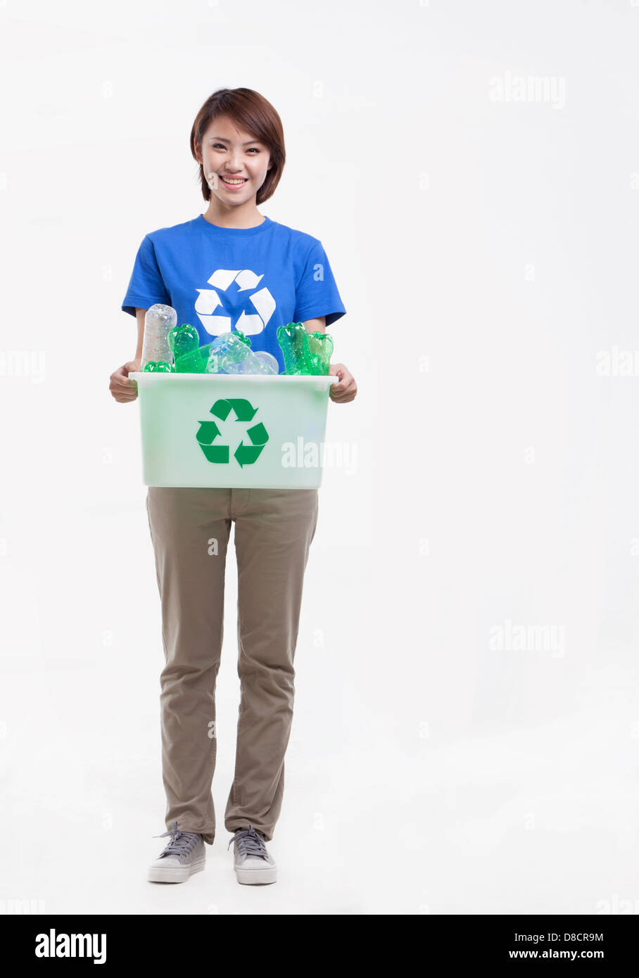 Portrait of young woman holding recycling bin, studio shot Banque D'Images