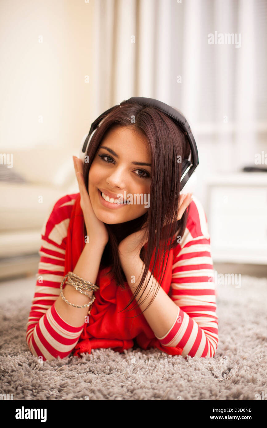 Belle jeune femme en costume lumineux profitant de la musique à la maison Banque D'Images