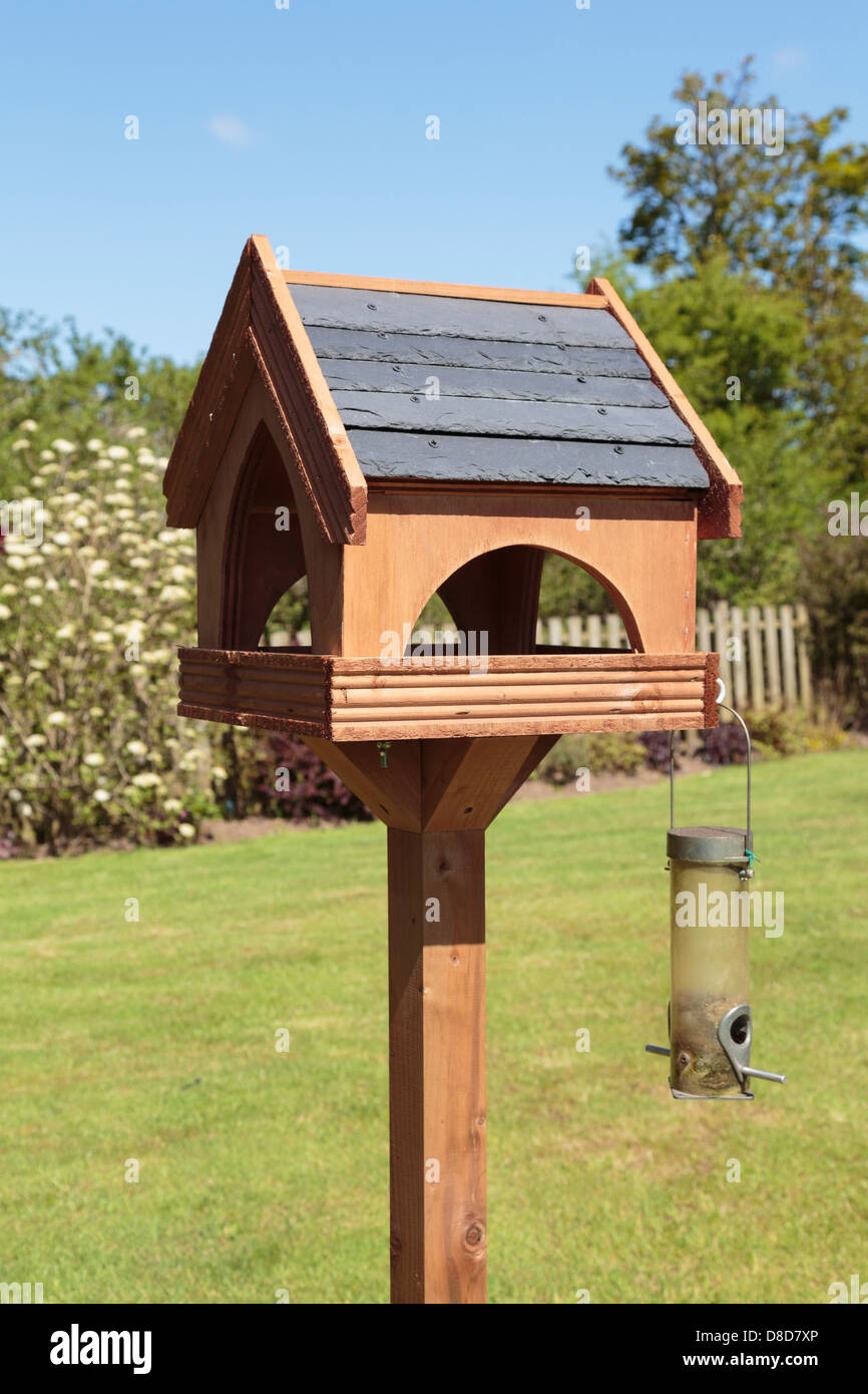 Tableau d'oiseaux en bois avec un toit en ardoise et un chargeur de semences dans le jardin en été. UK, Grande-Bretagne, Europe Banque D'Images
