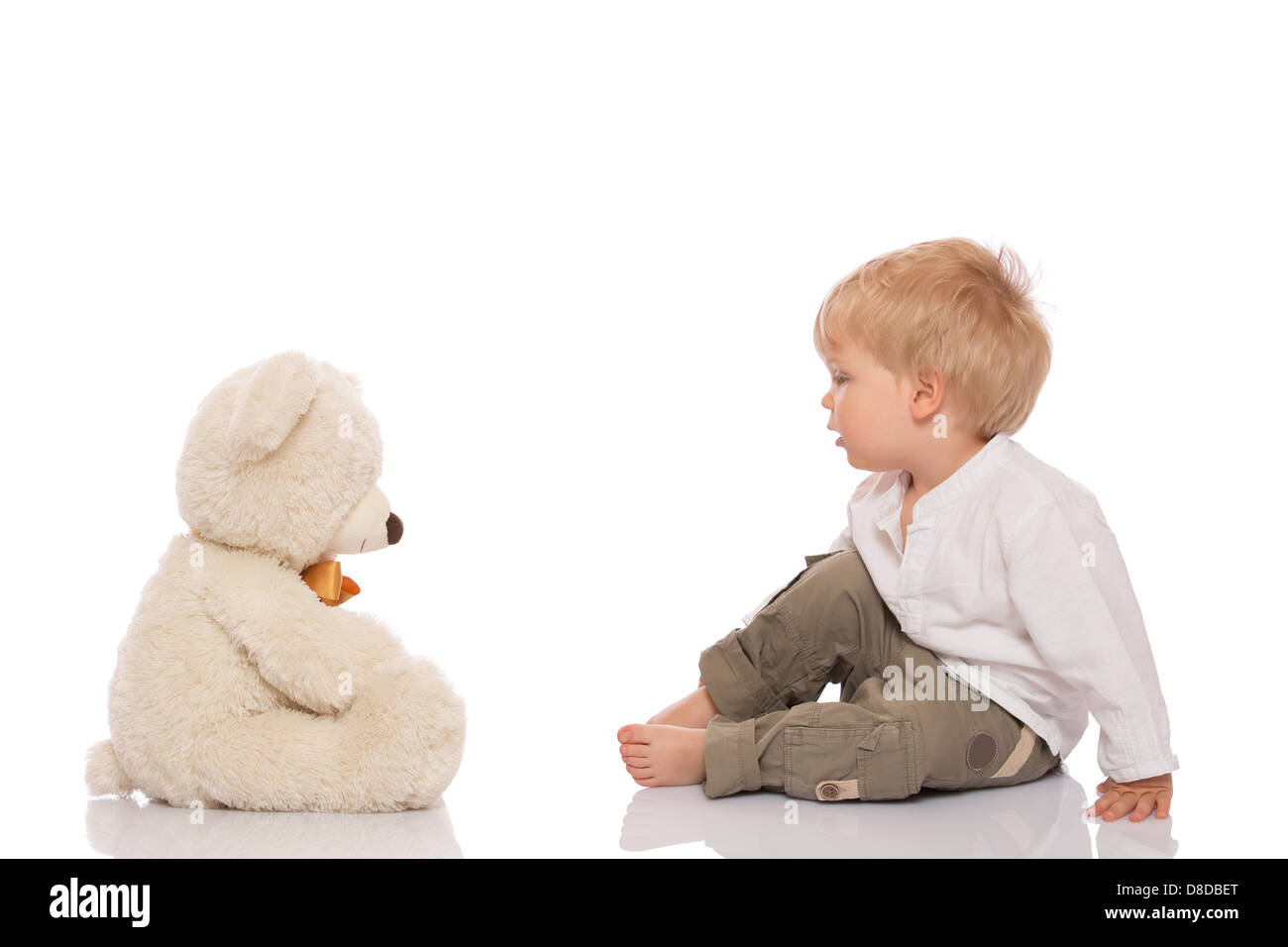 Petit garçon aux cheveux blonds assis sur le plancher et son ours en peluche. Isolé sur fond blanc. Banque D'Images