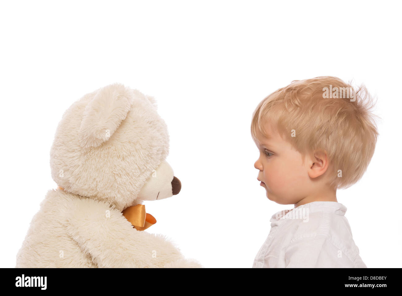 Enfant mignon avec des cheveux blonds à son ours en peluche. Isolé sur fond blanc. Banque D'Images