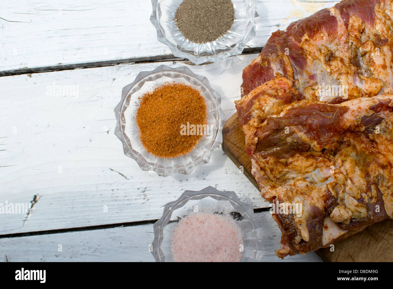 Côtes de porc cru assaisonné pour la cuisson sur une planche en bois Banque D'Images