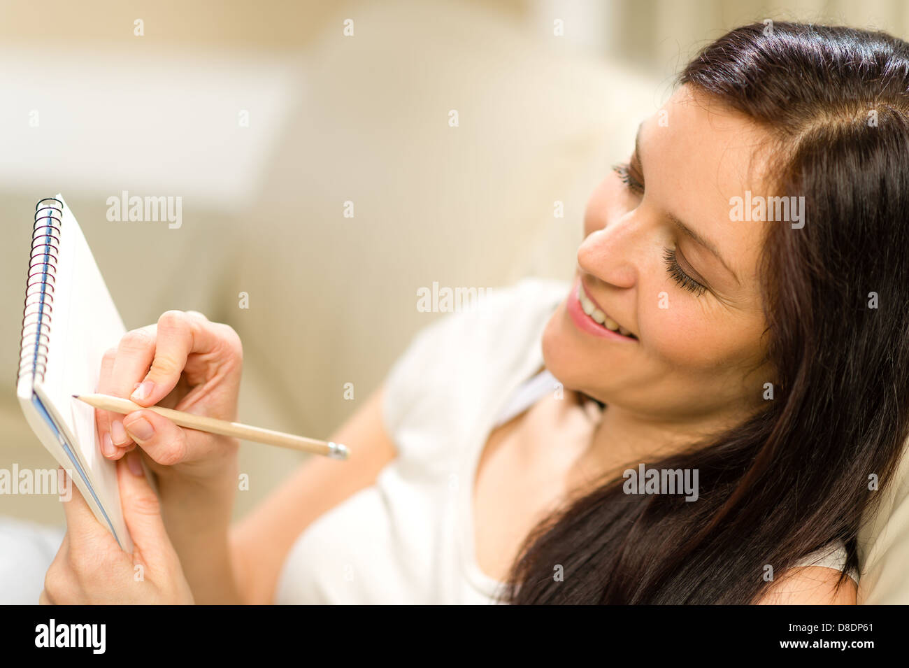 Femme heureuse prise de notes dans le bloc-notes à l'aide d'un crayon Banque D'Images