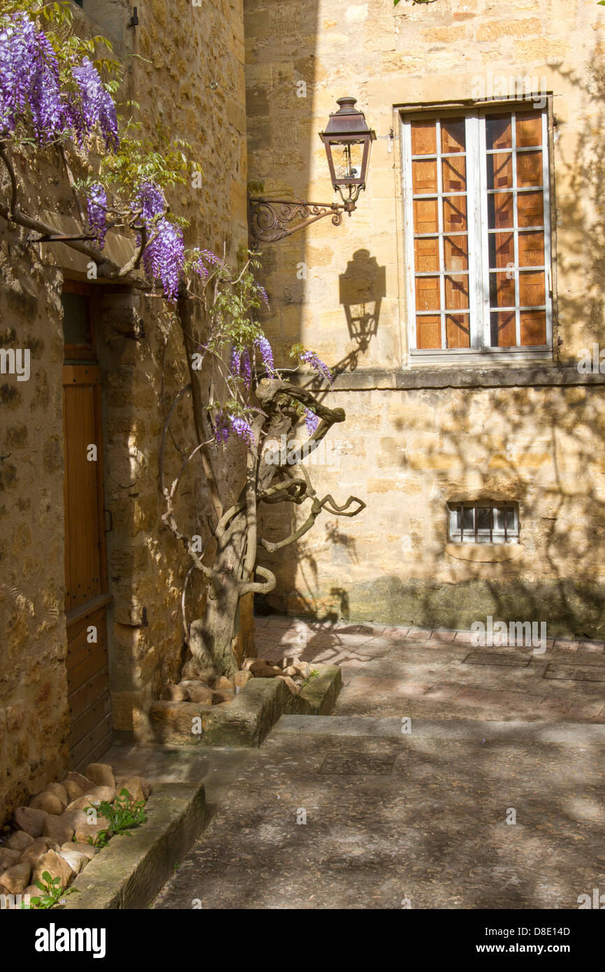 Lampadaire en fer forgé d'après-midi sur le mur de l'ombre des bâtiments en pierre médiévale dans la cour, Sarlat, Dordogne, France Banque D'Images