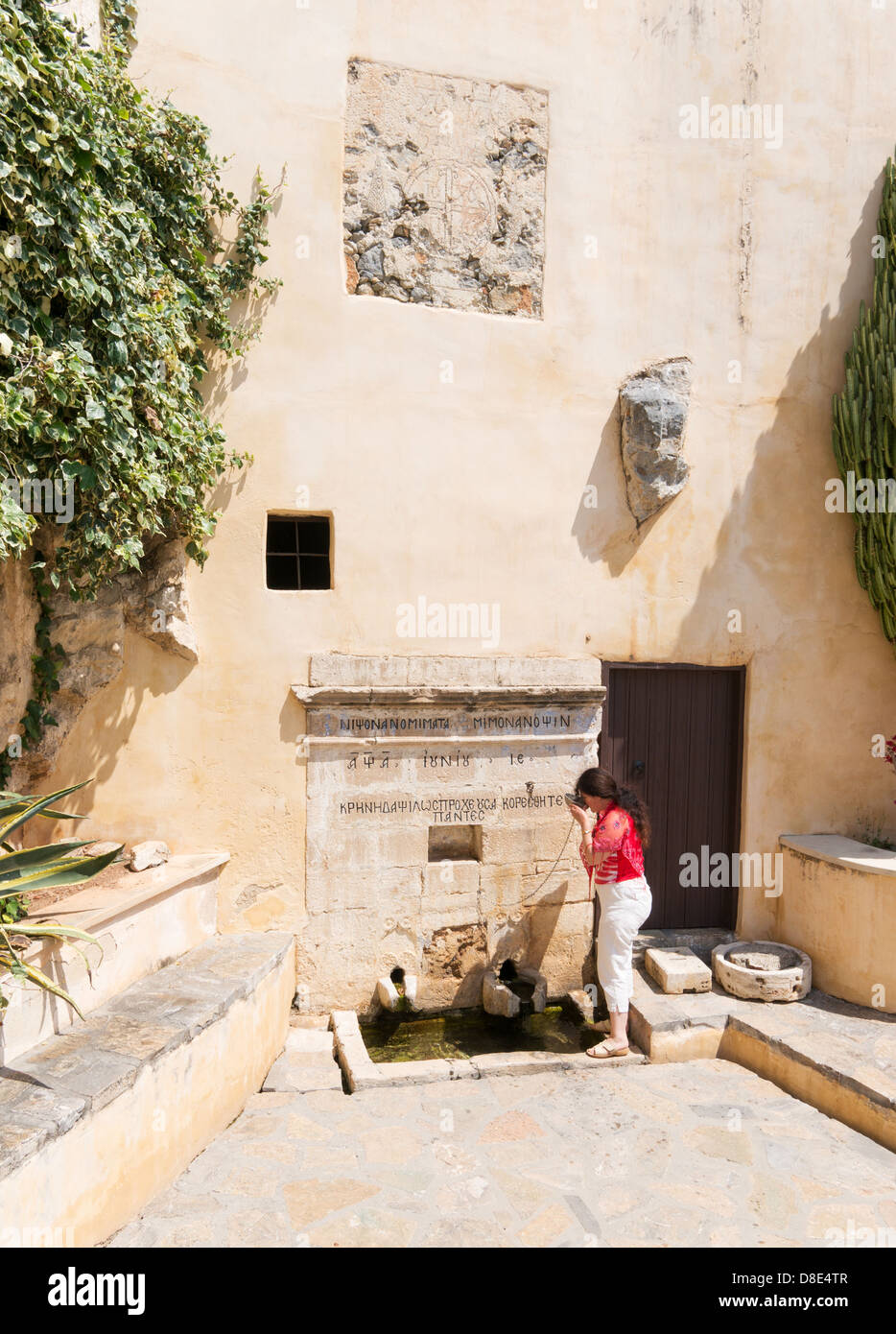 Femme buvant de l'eau de source dans le monastère Ayios Ioannis, Preveli, Crete Banque D'Images