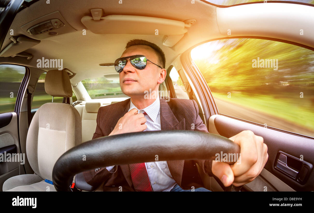 Homme en costume et lunettes de conduite sur une route dans la voiture  Photo Stock - Alamy