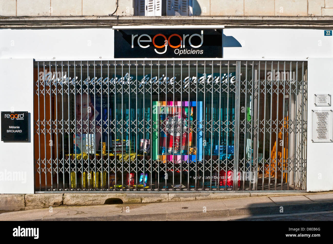 Grille de sécurité anti-vandalisme à travers la vitrine de l'opticien - France. Banque D'Images