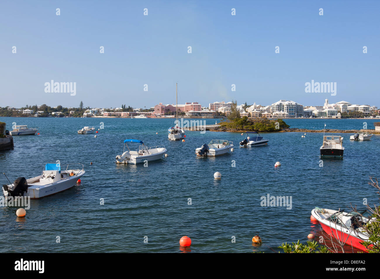 Les bateaux de plaisance amarrés dans une crique à sel électrique, les Bermudes. La ville de Hamilton est dans la distance. Banque D'Images