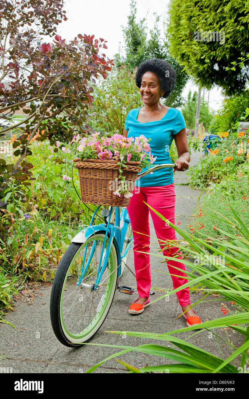 Woman riding bicycle rétro avec panier de fleurs Banque D'Images