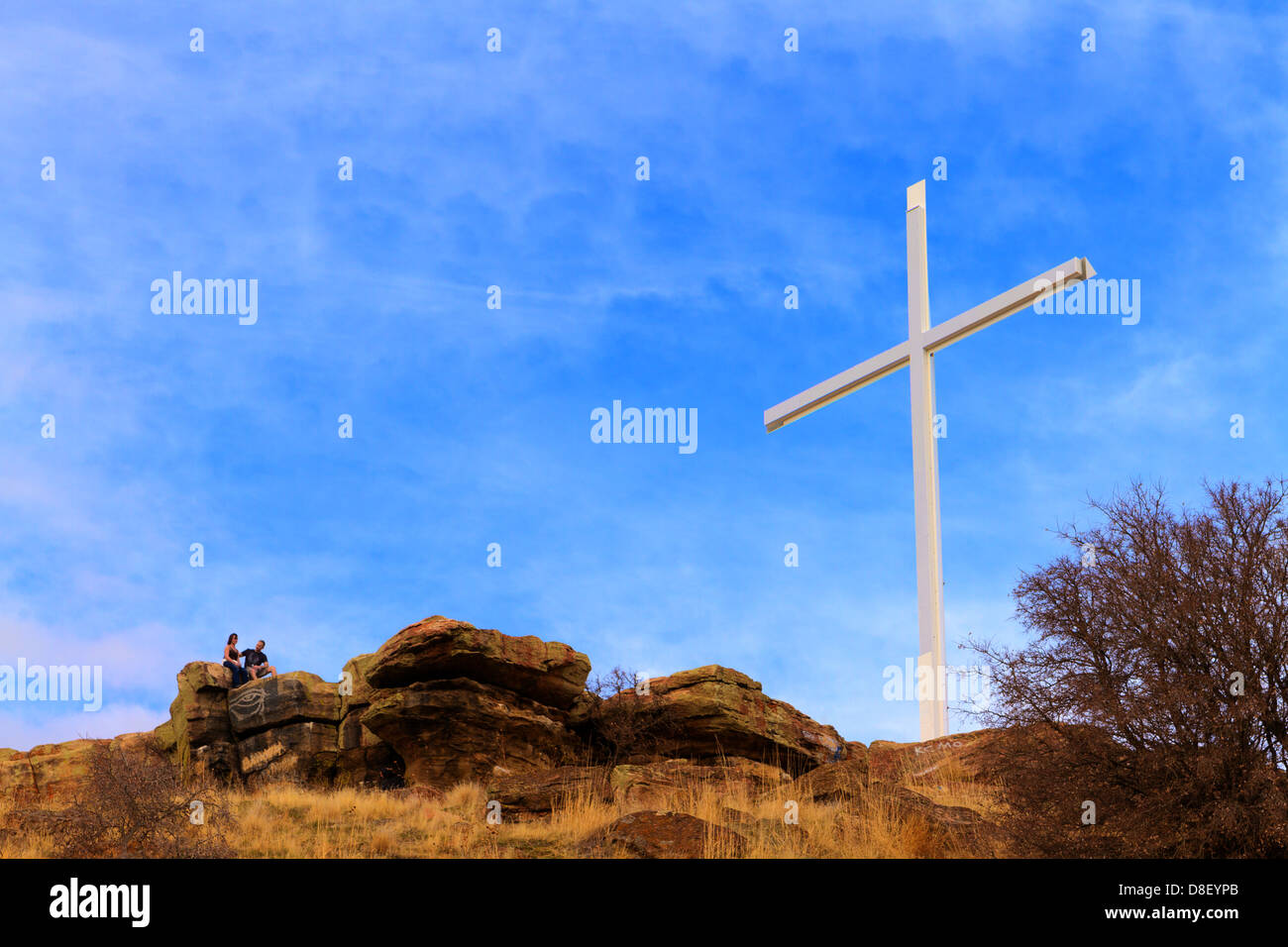 Gros plan sur une grande croix chrétienne blanche au sommet de Table Rock dans Boise contreforts avec deux personnes assis près de la base de Banque D'Images