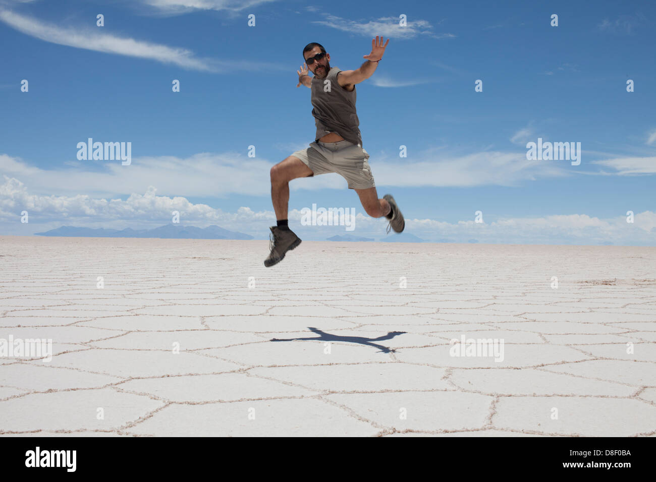 Homme passe dans le sombre paysage blanc du Salar de Uyuni en Bolivie Banque D'Images