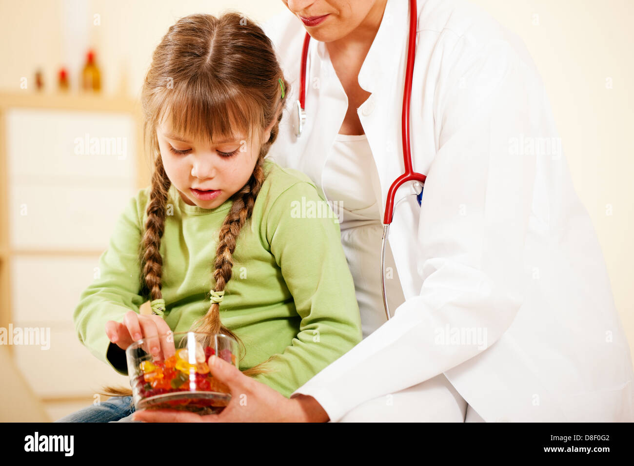 Femme médecin pédiatre donnant de bonbons (gomme ours) à peu patient après le traitement Banque D'Images