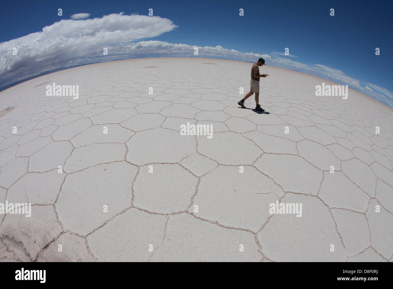 Homme perdu marche à travers les fissures de sel de Uyuni seul Banque D'Images