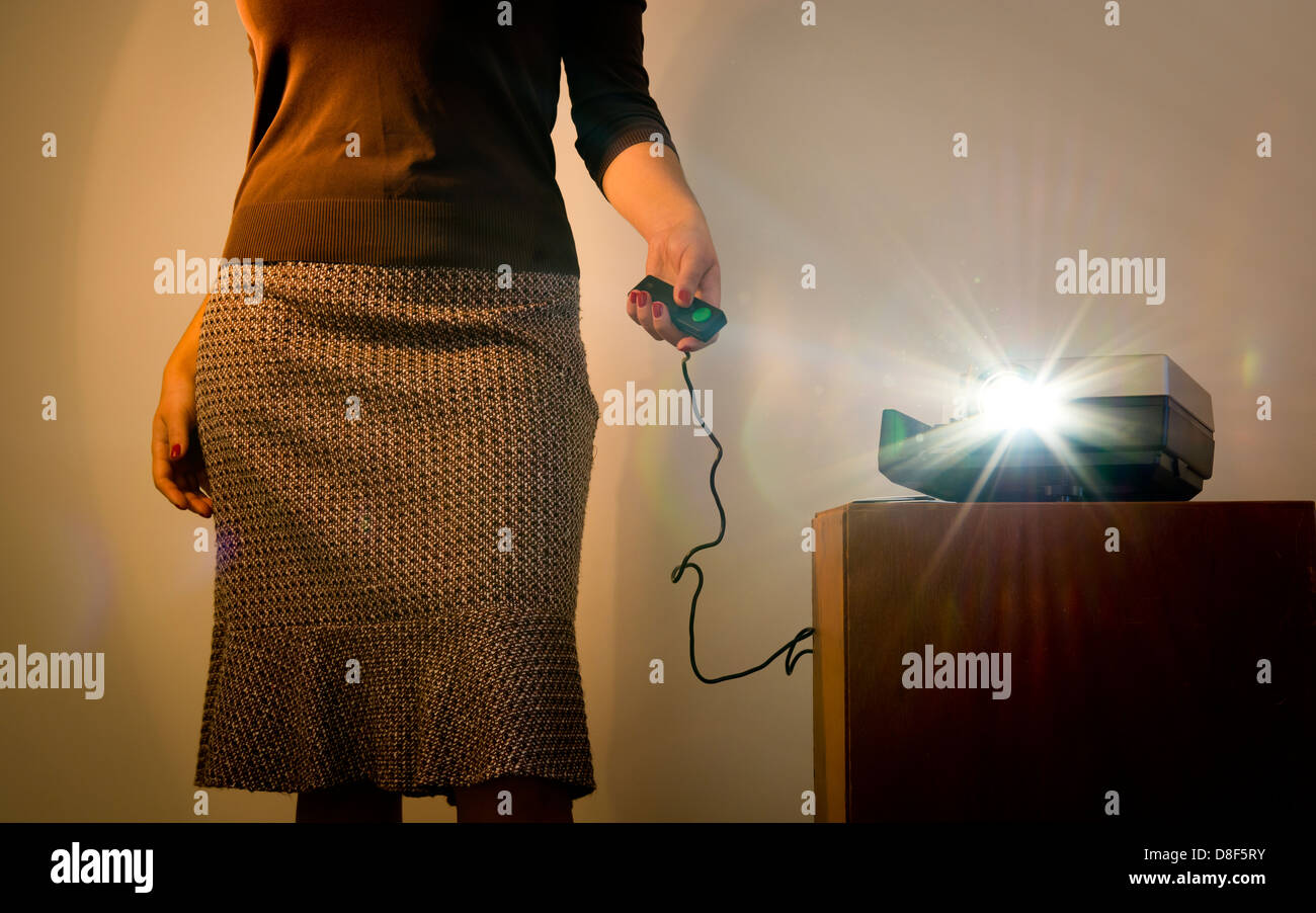 Femme de style rétro projecteur de diapositives d'exploitation avec une télécommande filaire et de reflets de lumière projecteur Banque D'Images