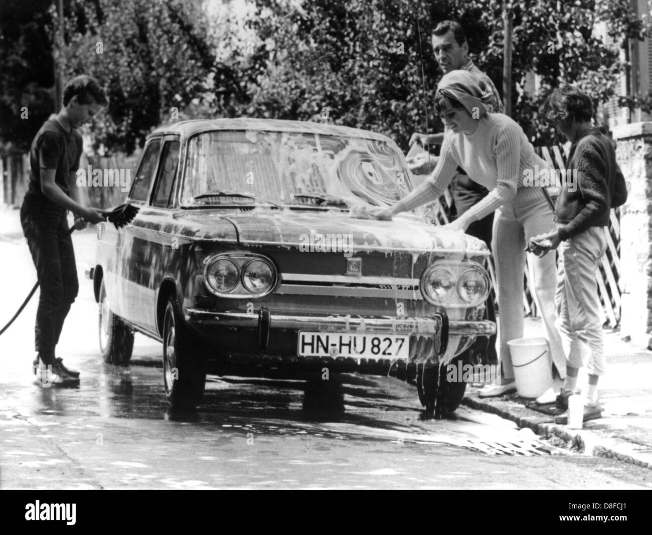Les Allemands ont toujours aimé lavent leur voiture le samedi. Père, mère et enfants laver leur voiture en face de leur maison, photographié en 1967. Banque D'Images