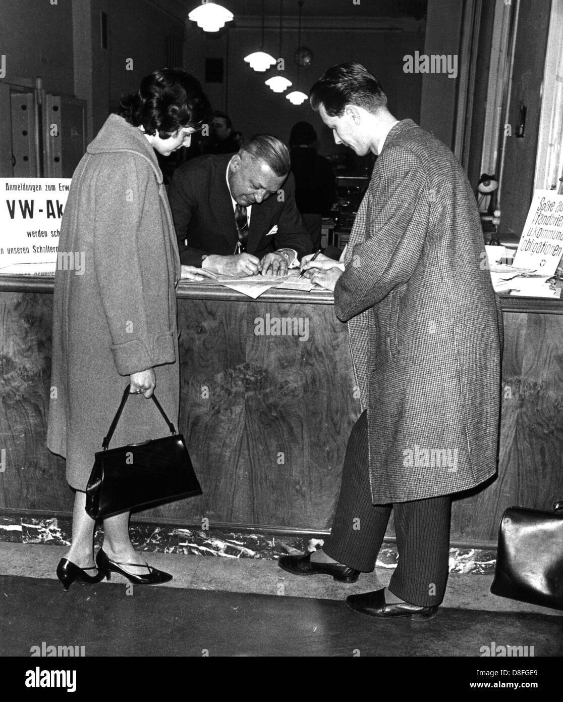 Un jeune couple fait l'acquisition de stocks de Volkswagen AG, photographié en janvier 1961. Banque D'Images