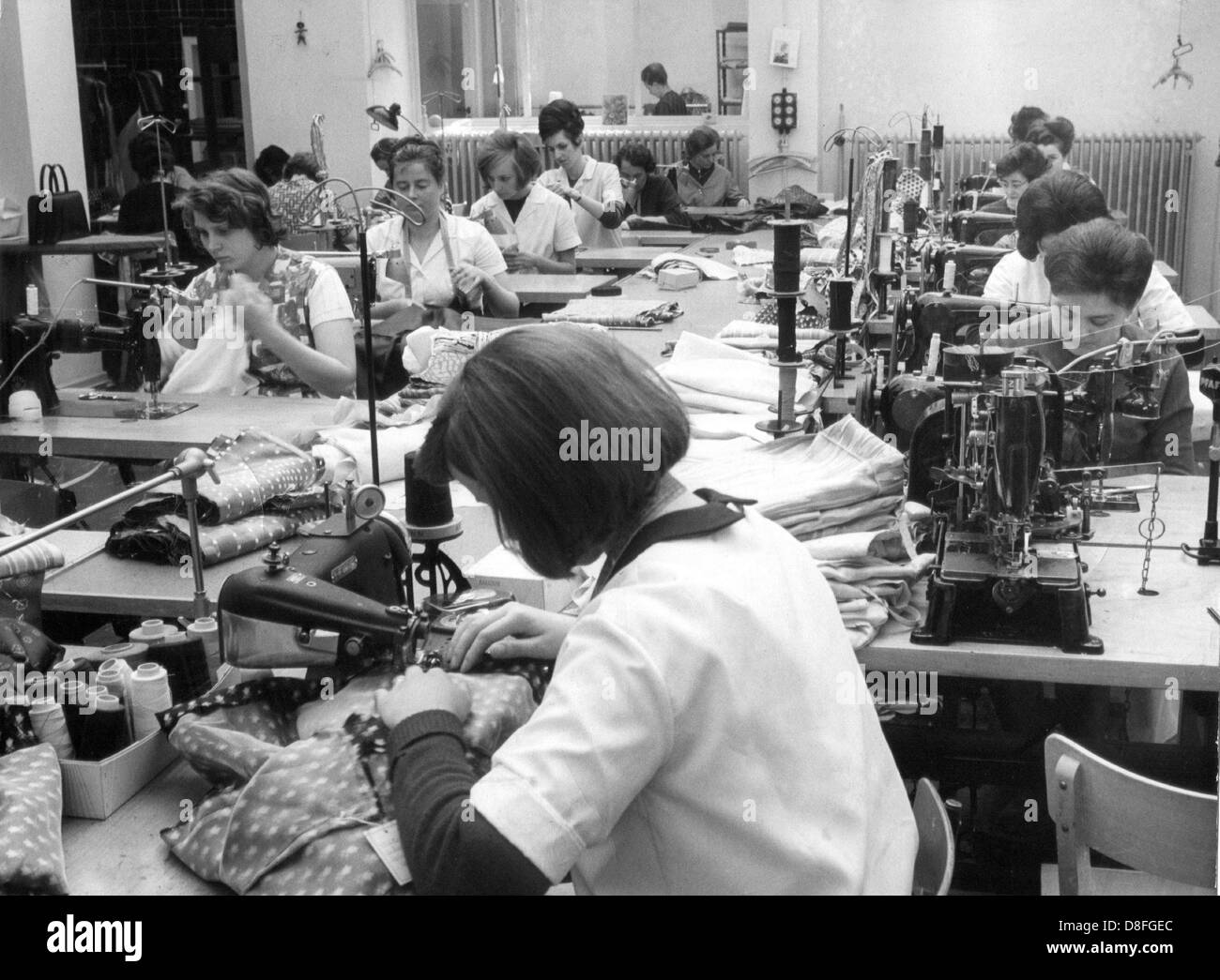 Les femmes travaillent à des machines à coudre dans une société du tailleur, photographié en 1965. Banque D'Images