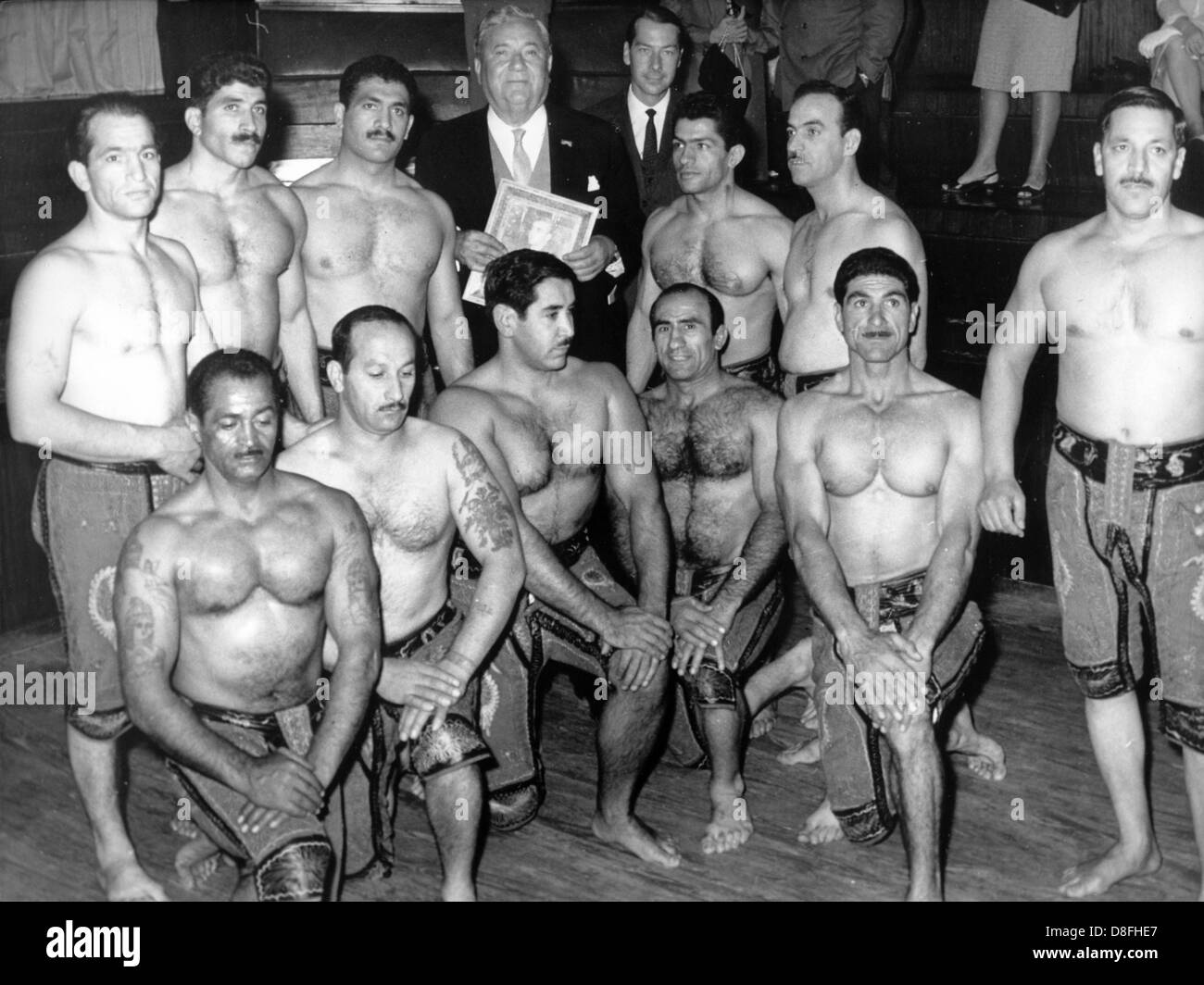 Avocat et homme politique Carlo Schmid (m, arrière) visite une école de sport à Téhéran (Iran) en octobre 1964 et est entouré par des hommes musclés. Banque D'Images