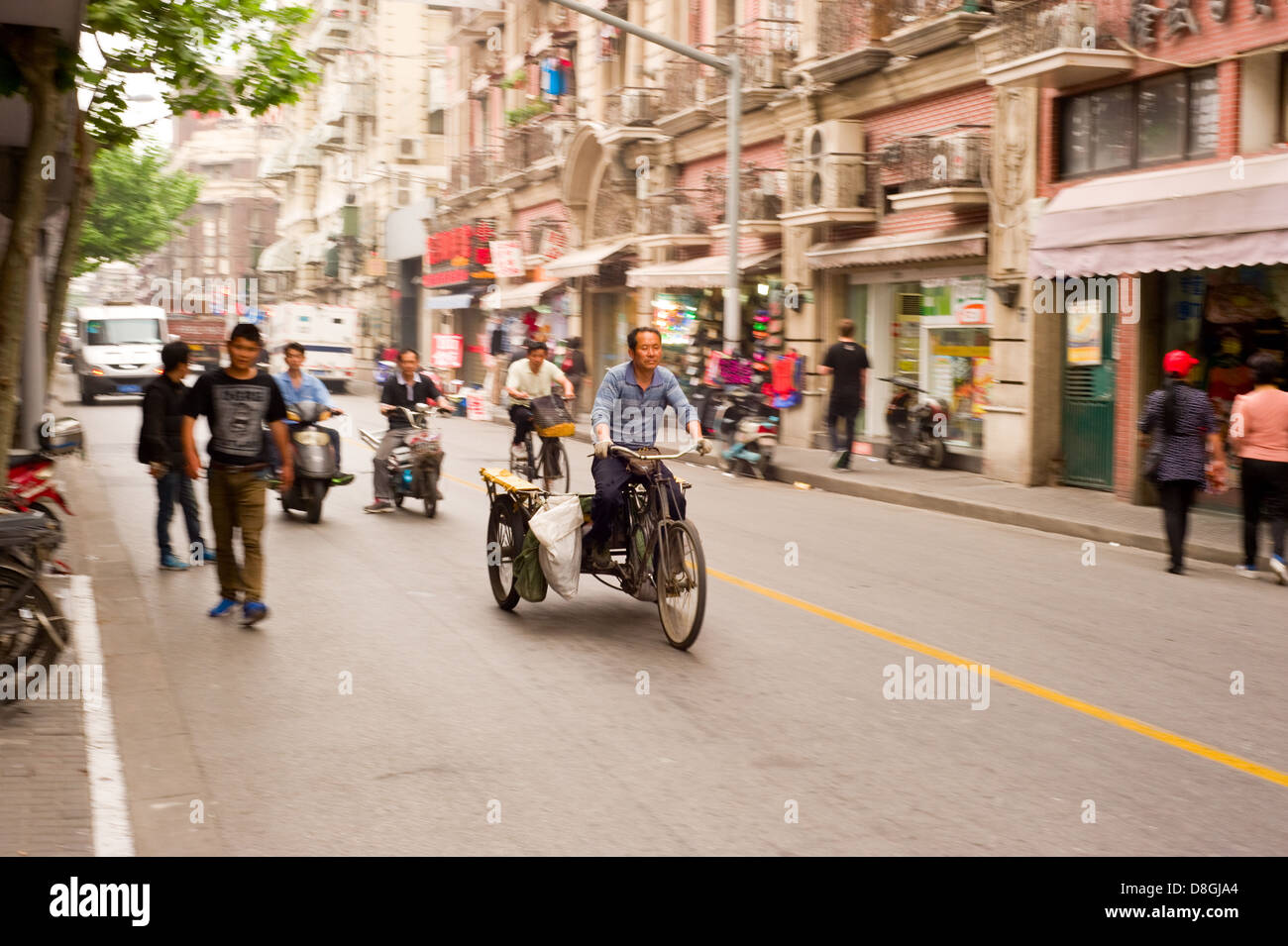 Un homme chevauche son vélo à trois roues dans une rue de Shanghai, Chine. Banque D'Images