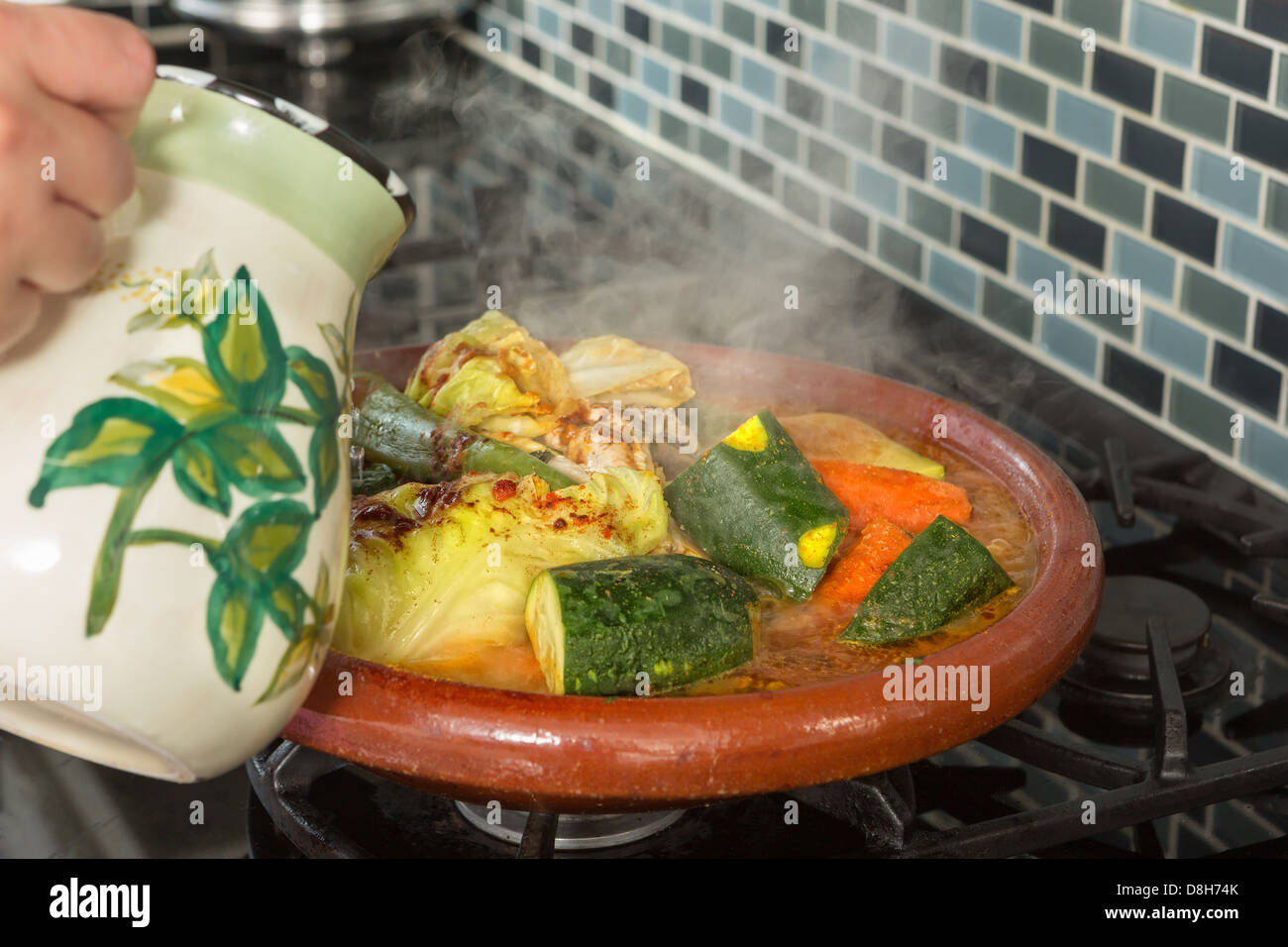 Femme marocaine ajoutant de l'eau à son plat tajine Banque D'Images