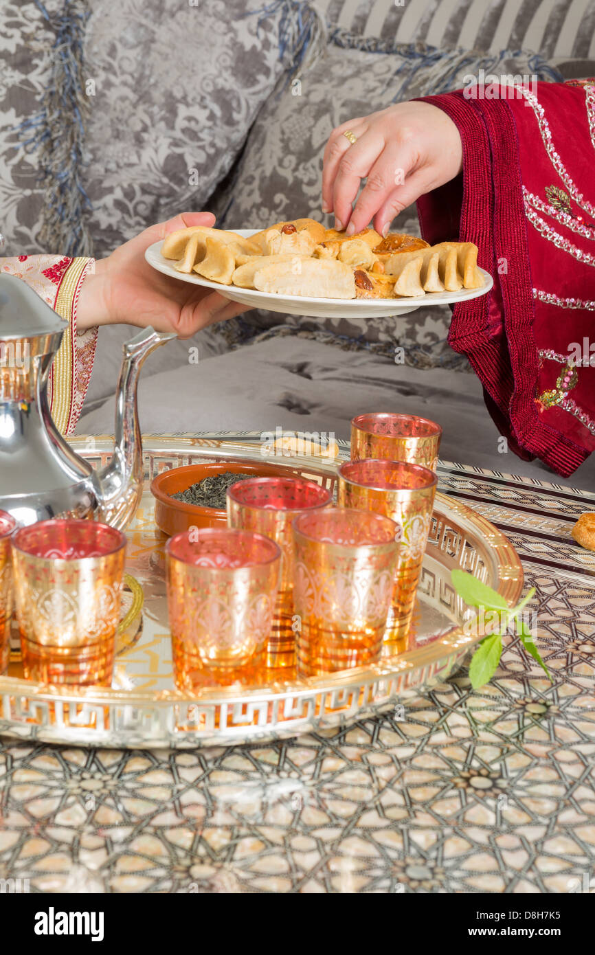 Mains d\u0027une femme marocaine ramadan présentant des gâteaux et du thé à un invité