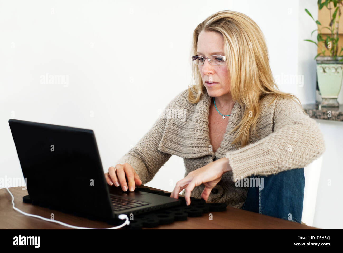 Une jolie femme de 40 ans portant des lunettes et travaillant sur son ordinateur portable à la maison Banque D'Images