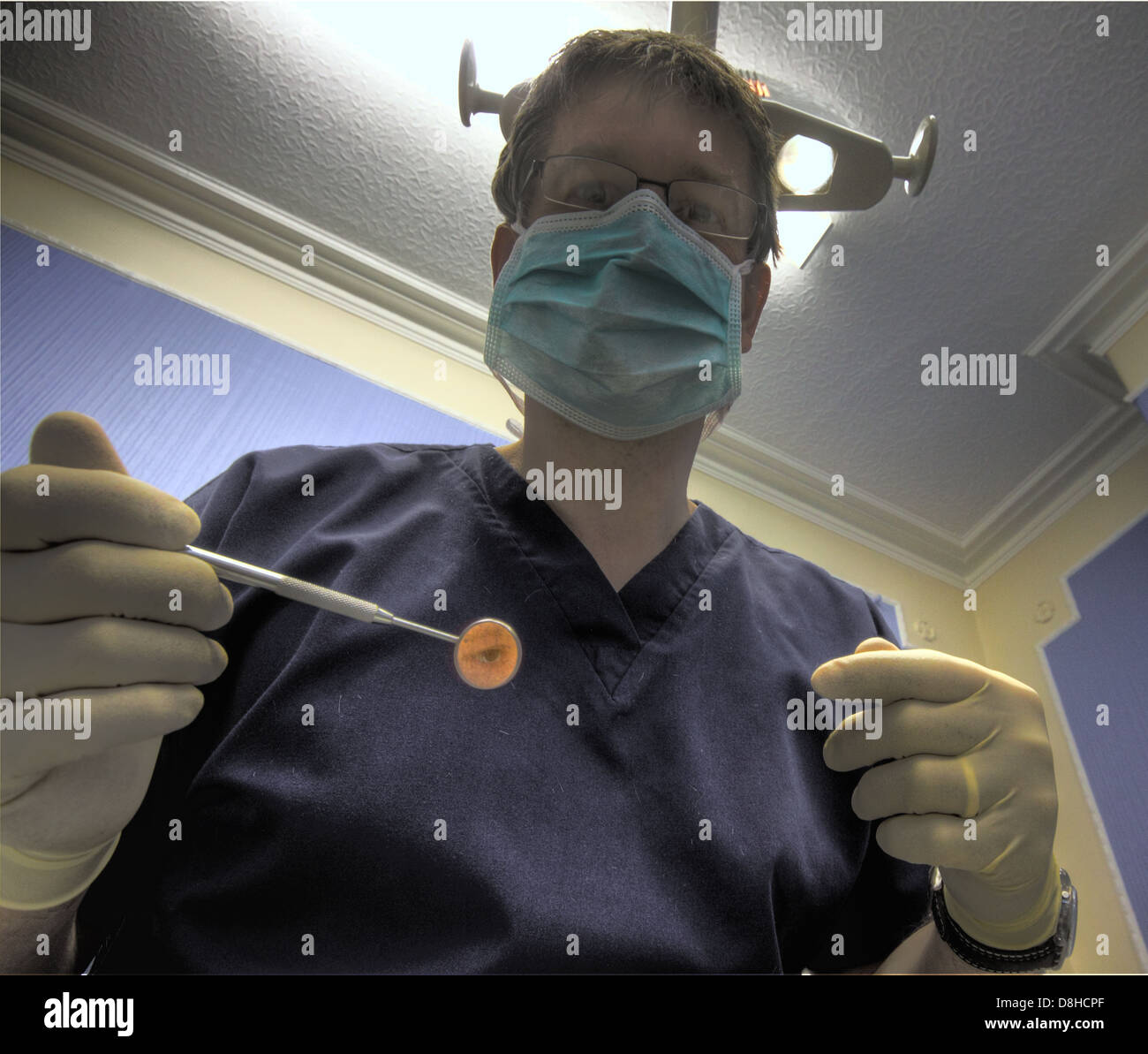 Un dentiste prêt à fonctionner sur un patient, tenant son miroir Banque D'Images