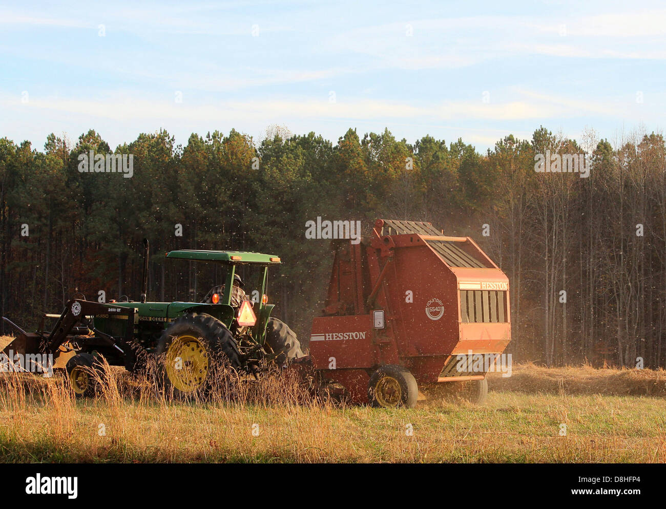 Une presse à balles de fourrage de tracteur est une machine agricole utilisée pour compacter le fourrage en balles pour faciliter le transport et le stockage. Il est essentiel pour une fenaison efficace dans les opérations agricoles. Banque D'Images