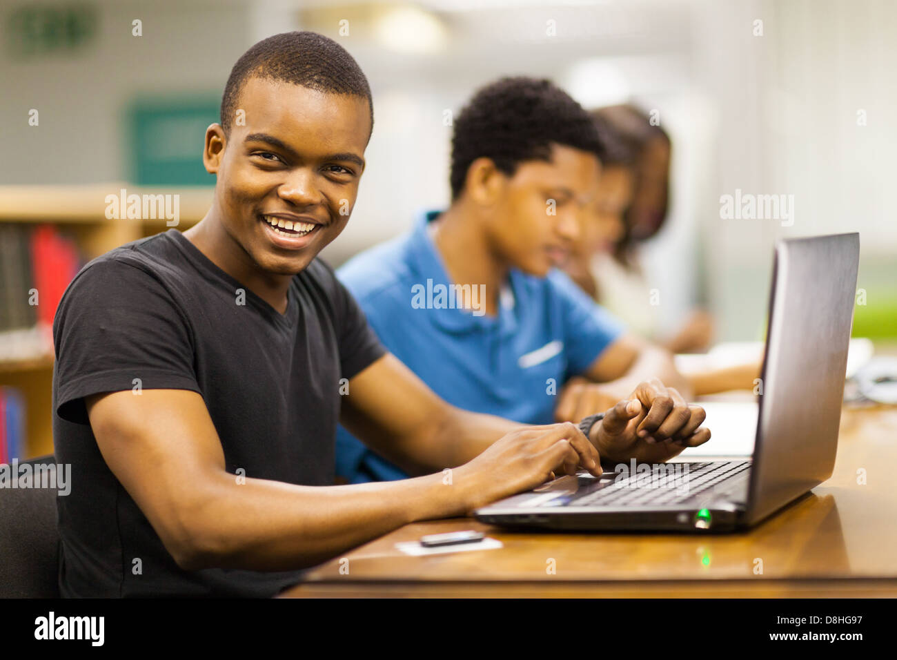 Heureux homme african college student using laptop in library Banque D'Images