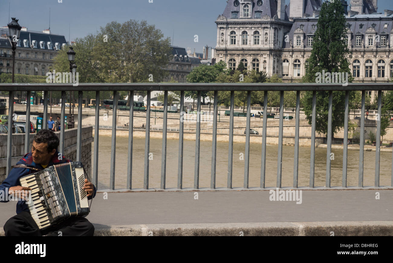 Paris, France. Un homme fait un accordéon sur le pont entre l'Île de la Cité et l'île Saint-Louis. Hôtel de Ville derrière Banque D'Images