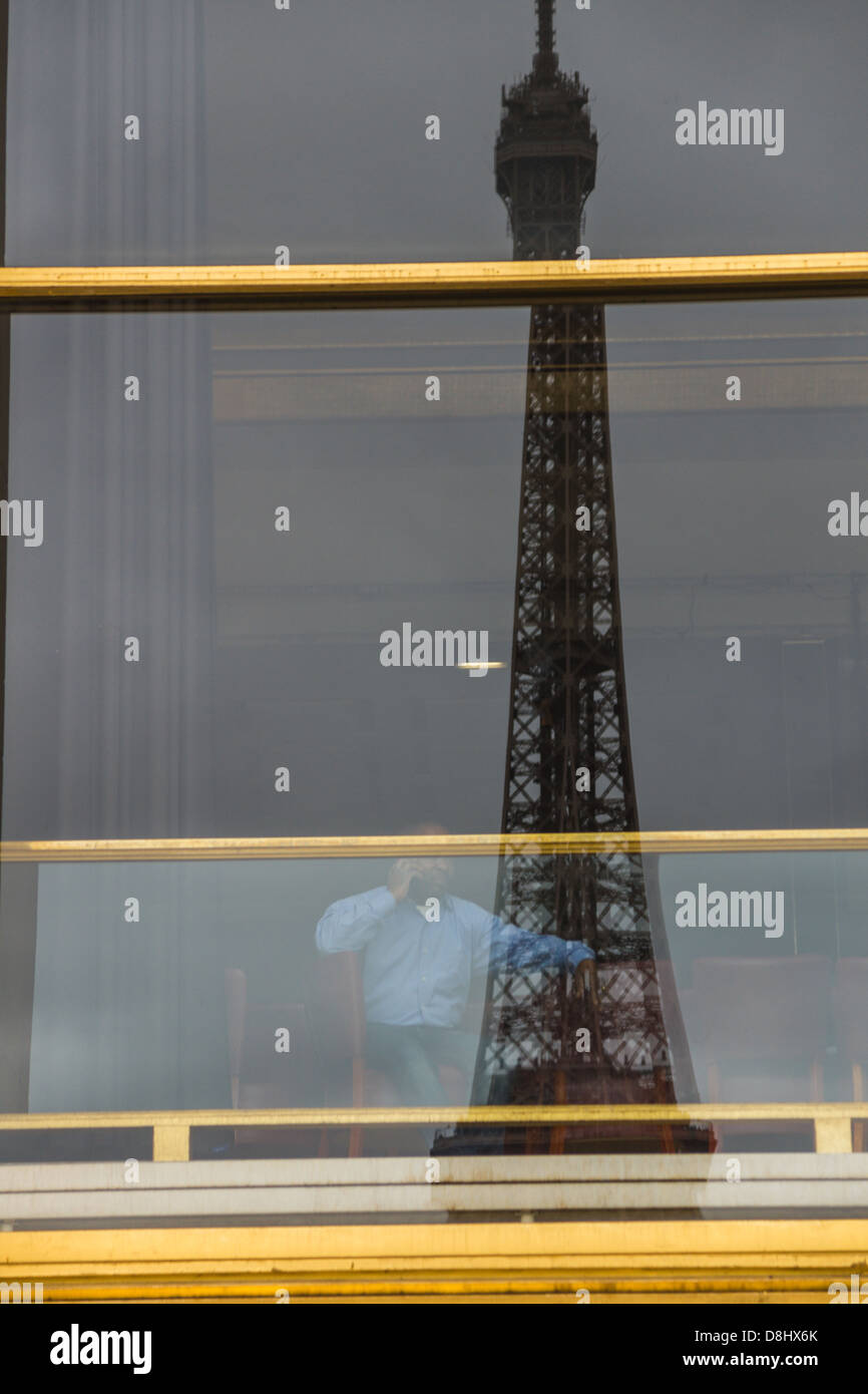 Paris, France. Un homme est assis dans la galerie du Théâtre national de Chaillot. La Tour Eiffel reflète dans les fenêtres Banque D'Images