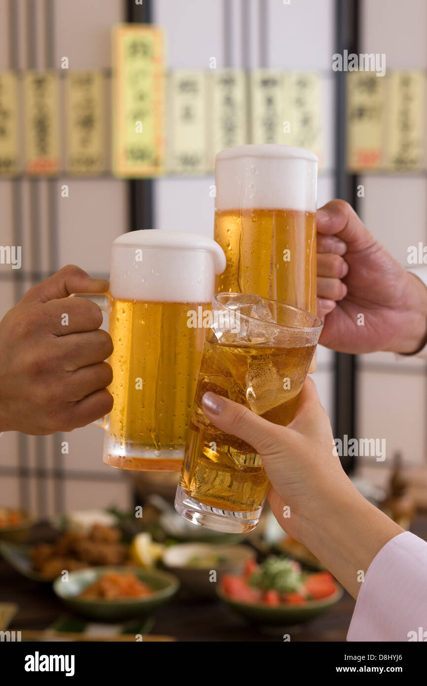 Trois personnes Toasting avec bière et Chu-Hi à Izakaya Banque D'Images